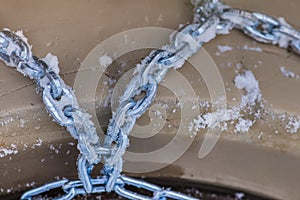 Wheel in the snow with safety and anti-skid chains. Loader or tractor with chains on wheels close-up. Driving safety in