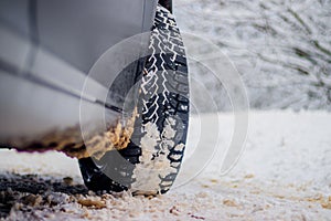 Wheel with spikes on a winter road. Winter road. Snow road. Car on the winter road. Footprints in the snow