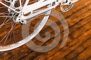 The wheel of a stylish bicycle with a white rim and a brown rubber tire, a chain, an asterisk on a stylish wooden background.