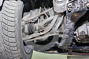 The wheel, suspension and chassis of a car standing on a car lift close-up