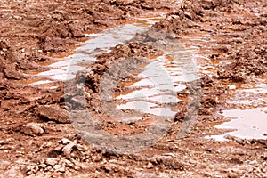 Wheel trace on road, puddle and mud after rain. Traces on soil of tractor, excavator, car, automotive tire tracks on muddy trail.