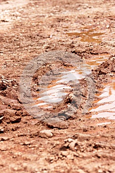 Wheel trace on road, puddle and mud after rain. Traces on soil of tractor, excavator, car, automotive tire tracks on muddy trail.