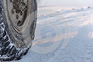 Wheel of a truck on snow-covered road, close up, copy space