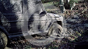 Wheel tyre closeup in a countryside landscape with a muddy road, dirty tires in mud. Mud and water splash in off-road