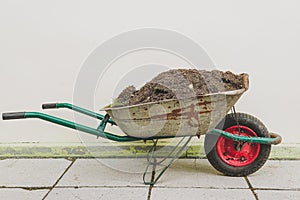 A wheelbarrow filled with earth.Garden wheelbarrow filled with peat soil on a farm
