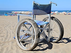 Wheelchair on the beach sand near the sea