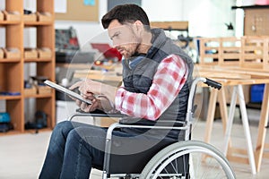 Wheelchair bound man using tablet in workshop