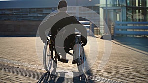 wheelchair-bound man is walking alone on city street, moving to lift for disabled people