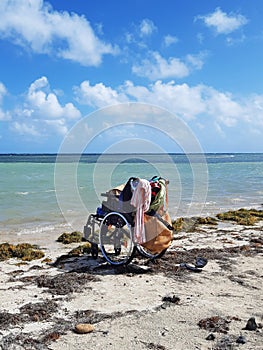 Wheelchair on the shore of wild Caribbean beach, turquoise waters and tropical blue sky. French Antilles. Fun and reduced mobility