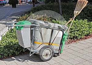 Wheeled garbage can with broom on the street