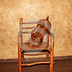 The wheeled lyre is a stringed musical instrument on a wooden chair.