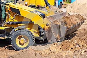 Wheeled tractor bulldozer levels the earthen area at the workplace