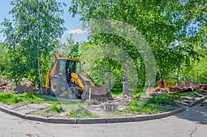 A wheeled universal backhoe loader digs a trench