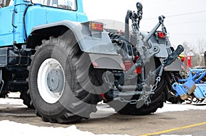 Wheels of back view of new tractor in snowy weather. Agricultura