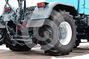 Wheels of back view of new tractor in snowy weather. Agricultural vehicle back