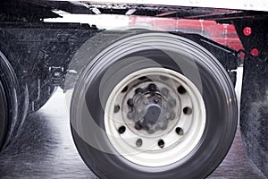 Wheels of big rig semi truck raises rain dust from the wet road