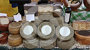 Wheels of different types of Pecorino on a shelf at the market. In the middle the specialty cheese ripened with hay