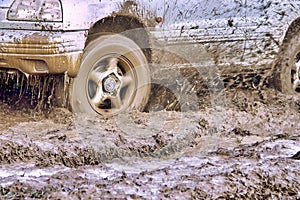 Wheels of the offroader are slipping in the mud and splashing slush on the car