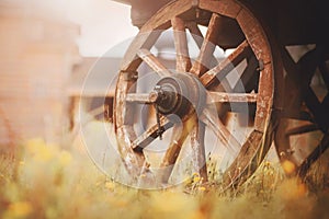 The wheels of an old wooden cart, which stands on a field, and on the background of an old wooden church. Farming and harvesting.