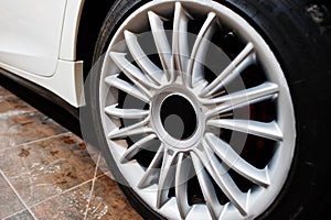 Wheels of white new luxury sport car in detailing garage