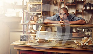 Where are all the customers. Shot of a young man standing behind the counter of his store and looking downhearted.