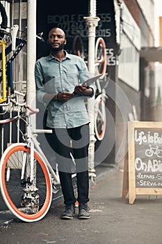 Where is that delivery. Full length shot of a handsome young man standing outside his bicycle shop and looking