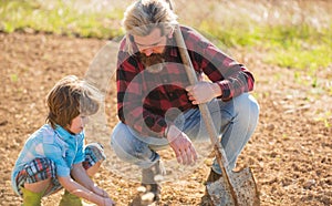 Where food comes from. Teaching son growing plants. Planting plants. Works in field. Father farmer instruct baby how to