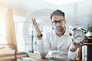 Where has time disappeared to. Portrait of a young businessman looking stressed out while holding a clock in an office.