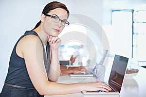 This is where I make my business dreams a reality. Portrait of a young businesswoman working at her desk in an office.
