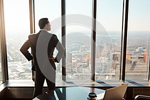 This is where I will build my empire. Rearview shot of a young businessman looking out the window in an office.