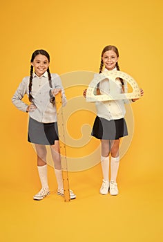 Where pupils achieving excellence together. Cute pupils holding protractor and ruler on yellow background. Little pupils