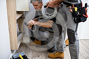 Where quality is important. Cropped shot of aged electrician, repairman in uniform working, examining cable, checking