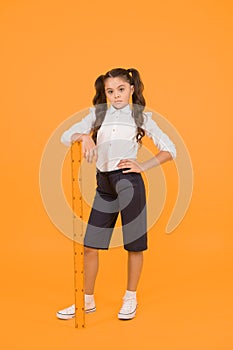 Where student comes first. Serious small student holding wooden ruler on yellow background. Little student learning