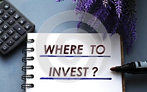 WHERE TO INVEST? - words are written on a notepad with a marker, calculator and lavender sprigs