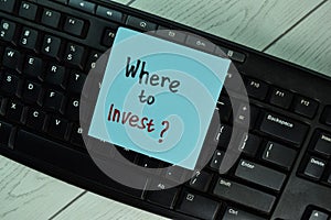 Where to Invest? write on sticky notes isolated on Wooden Table