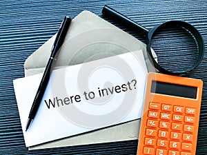 Where to invest written on sticky note with a pen on brown envelope.