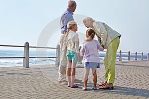 Where to next. grandparents walking hand in hand with their granddaughters on a promanade.