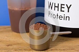 Whey Protein. Close up of scoop with chocolate powder, jar and s