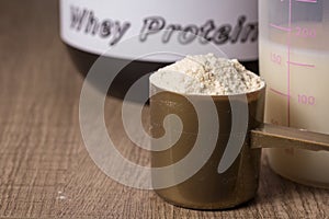 Whey Protein. Golden scoop with vanilla flavour powder, shaker a