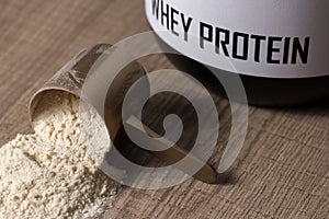 Whey Protein. Golden scoop on wooden background with vanilla pow