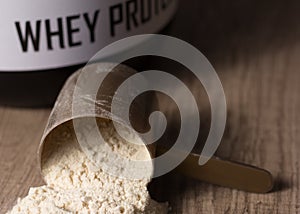 Whey Protein. Golden scoop on wooden background with vanilla pow