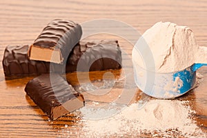 Whey protein powder in measuring scoop and chocolate protein bar