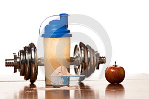 Whey protein powder in scoop, dumbbell, meter tape and plastic s