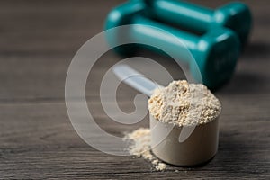 Whey protein powder in scoop and dumbbells. Sports drink, nutrition for muscle growth