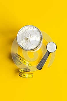 Whey protein in scoop and jar with tape measure. Sport nutrition