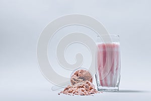 Whey protein shake in a glass and overturned scoop