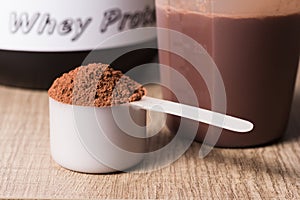 Whey Protein. White scoop with chocolate flavour powder, shaker