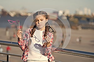 Which props to choose. Doubting small girl choosing glasses props. Adorable little child holding photobooth props on