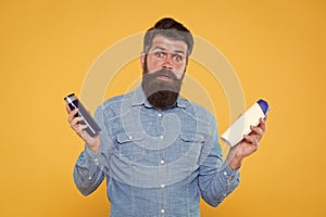 Which soap best. Bearded man hold soap bottles yellow background. Hipster choose liquid soap. For washing in bath or