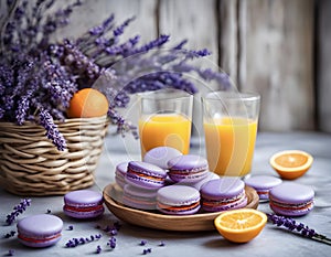 Whicker basket with purple and orange macarons near lavender flowers, fresh oranges and orange juice